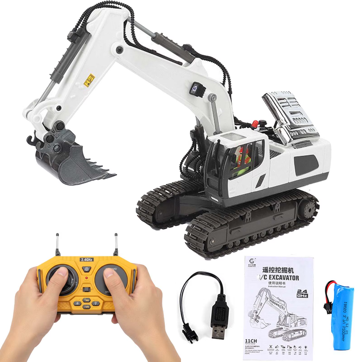 White tracked RC excavator with a grey metal bucket and raised boom, shown with the yellow two-stick remote, USB charging lead, manual and rechargeable battery