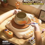 Cat pottery wheel in use: a cream cat-shaped electric wheel with a clay bowl on the turntable being painted, paint pots and brushes beside it